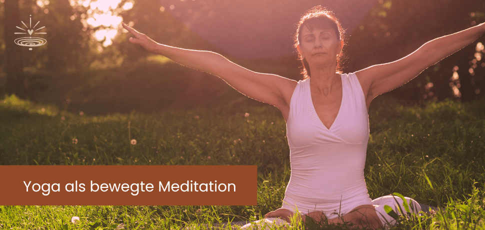 Eine dunkelhaarige Frau mittleren Alters sitzt im Schneidersitz auf einer Wiese am Waldrand, Augen geschlossen und macht Yoga. Ihre Arme sind weit zu den Seiten ausgestreckt: Yoga als bewegte Meditation.
